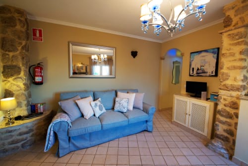 Sofá azul en luminoso apartamento estudio de La Vista Medina Stays, Medina Sidonia, con paredes de piedra y suelo de baldosas