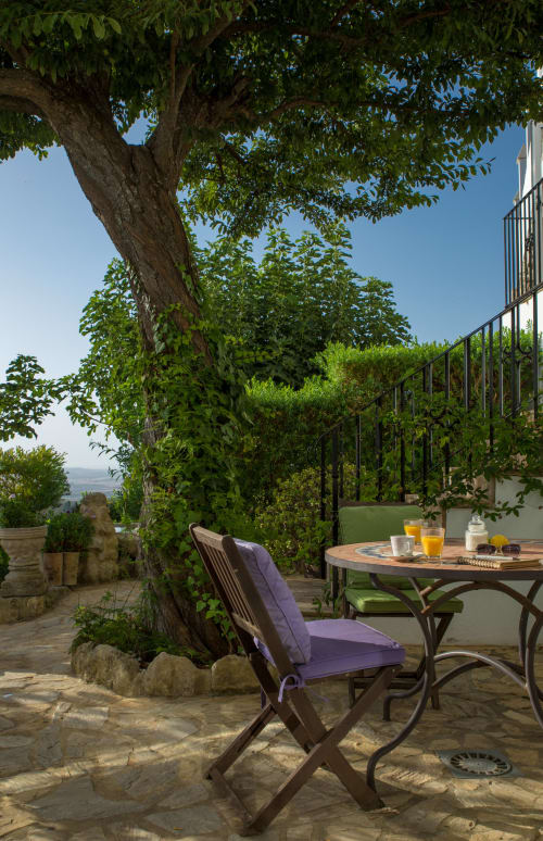 Terraza sombreada en La Vista Medina Stays con silla morada, mesa de comedor y vistas panorámicas del valle en Medina Sidonia, Andalucía