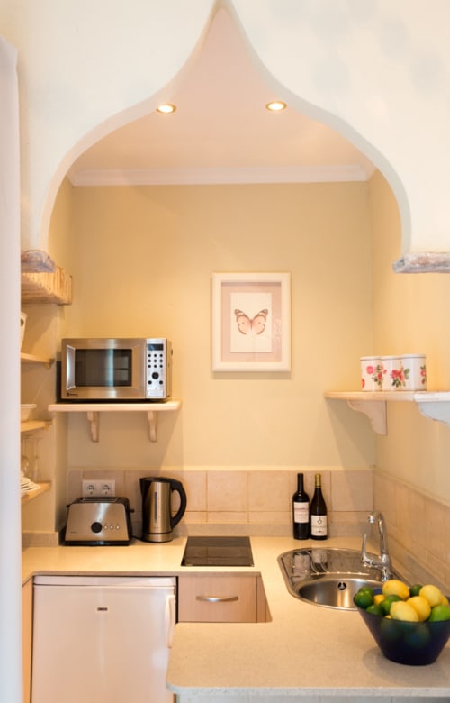 Pequeña cocina en estudio La Vista de Medina con microondas, fregadero, estufa y paredes amarillas en Medina Sidonia