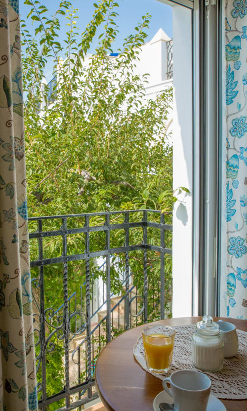 Vista del desayuno en el balcón del estudio La Vista de Medina en Medina Sidonia con café, zumo y exuberante jardín interior
