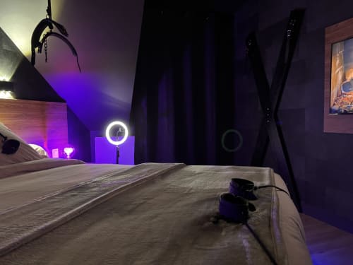 Modern hotel bedroom with purple ambient lighting, ring light, and adult entertainment setup at Love Room hotel in Vannes