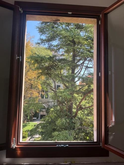 Finestra aperta della Casanova Hideaway B&B a Venezia con vista sulla corte, alberi e edificio storico