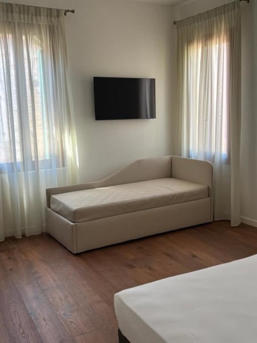 Letto daybed beige nella luminosa suite Casanova Hideaway con TV, parquet e tende trasparenti a Venezia