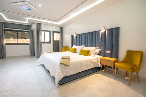Modern Family Room at Riad Gold Hôtel in Azrou with blue upholstered bed, yellow accents, marble floors, and garden views