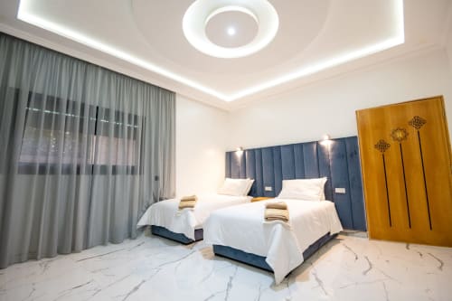 Modern double bedroom with twin beds, blue headboard, marble floor, and garden views at Riad Gold Hôtel in Azrou, Morocco
