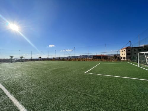 Artificial turf soccer field at Riad Gold Hôtel in Azrou, Morocco with goal post and mountains in background