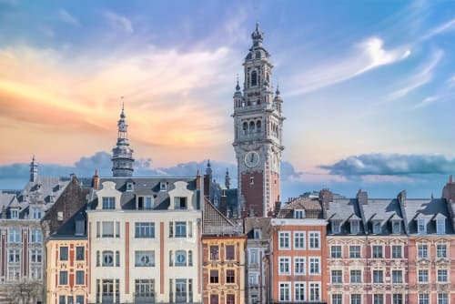 Colorful historic buildings with bell tower in Bourbourg, France at sunset