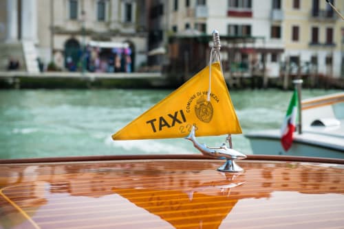 Bandiera gialla del vaporetto veneziano su barca con bandiera italiana, edifici del Canal Grande sullo sfondo, Venezia Italia