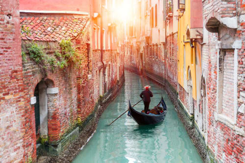 Gondola sul canale di Venezia circondato da edifici in mattoni rossi al tramonto, ubicazione del B&B Casanova Hideaway