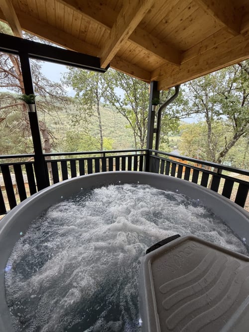Baignoire à remous avec eau bouillonnante sur une terrasse en bois dominant les montagnes forestières du Belvédère