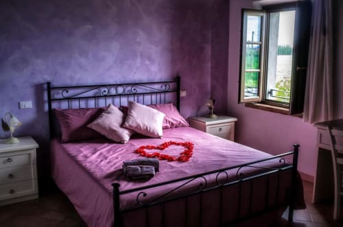 Romantic purple bedroom at Il Casale di David B&B in Pontedera with black iron bed and red rose heart