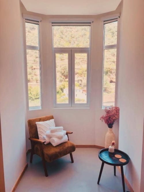 Cozy bay window nook at Casa Tawny with brown chair, blue side table, and valley views in Pinhão