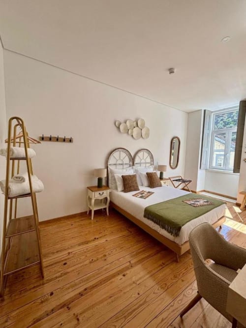 Bright bedroom at Casa Tawny guesthouse in Pinhão with wooden floors, metal bed frame, and neutral décor