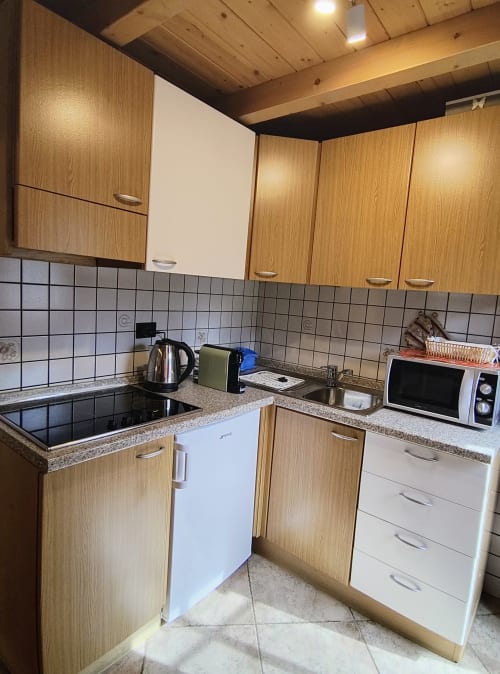 Cucina moderna nell'appartamento Al Dos a Livigno con mobili in legno, rivestimento in piastrelle, piano in granito e elettrodomestici