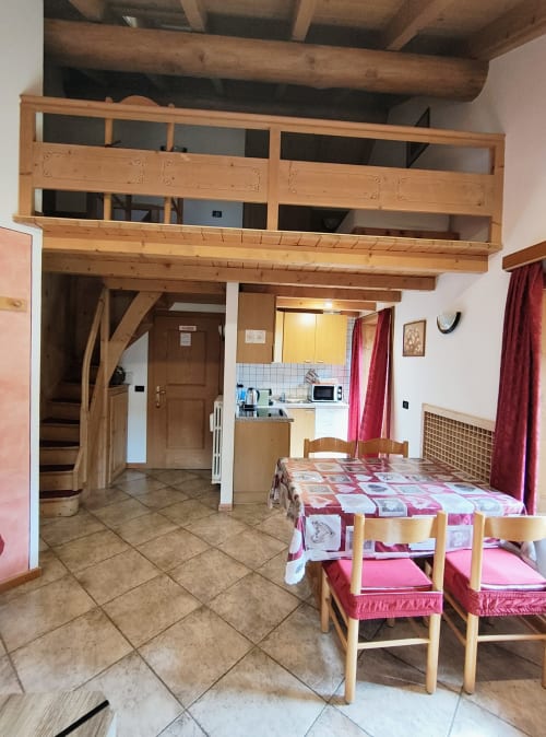 Bilocale Al Dos a Livigno con travi in legno, tavolo da pranzo, angolo cottura e vista sulle montagne