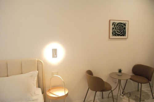 Camera doppia moderna presso Le Dimore Del Duca Roma con arredamento minimalista, lampada da parete circolare e zona living con tavolino.