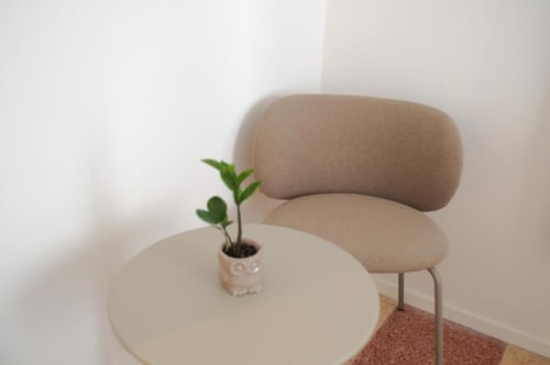 Poltrona in tessuto beige accanto a tavolo rotondo bianco con piccola pianta in vaso presso Le Dimore Del Duca Roma