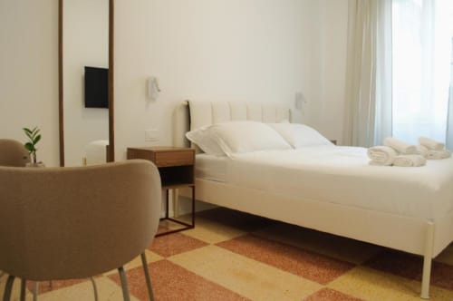 Camera matrimoniale moderna presso Le Dimore Del Duca Roma con biancheria crema, arredamento neutro, poltrona e vista sulla corte interna