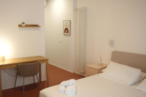Camera Tripla Moderna presso Le Dimore Del Duca Roma con letto, scrivania, arredamenti in legno e radiatore bianco a Roma