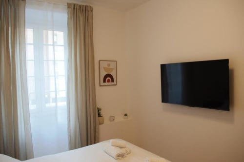 Moderna camera doppia presso Le Dimore Del Duca Roma con TV a schermo piatto, letto con asciugamani, finestra con vista su cortile interno, e