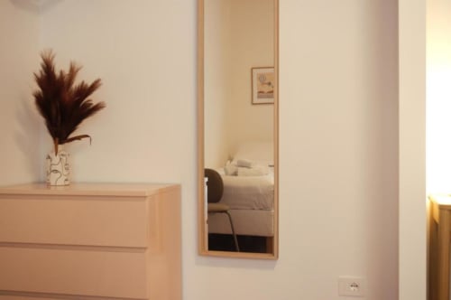 Elegante ingresso di camera d'hotel presso Le Dimore Del Duca Roma con cassettiera in legno, decorazione con erbe della pampa scure e specchio riflettente