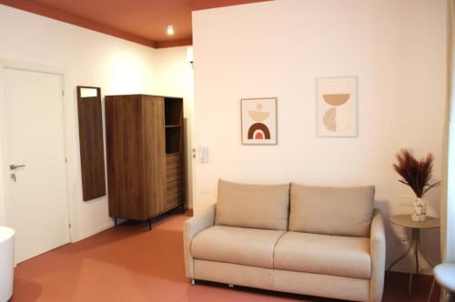 Divano beige in moderna camera Quadrupla presso Le Dimore Del Duca Roma, con guardaroba in legno e arte minimalista a parete