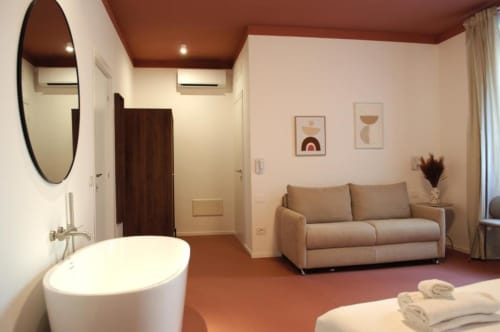 Camera Quadrupla Moderna con Vasca presso Le Dimore Del Duca Roma con divano letto, specchio rotondo e vasca indipendente