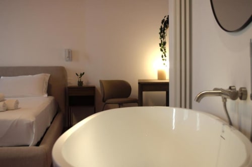 Camera da letto moderna con vasca indipendente, letto, poltrona e illuminazione calda presso Le Dimore Del Duca Roma