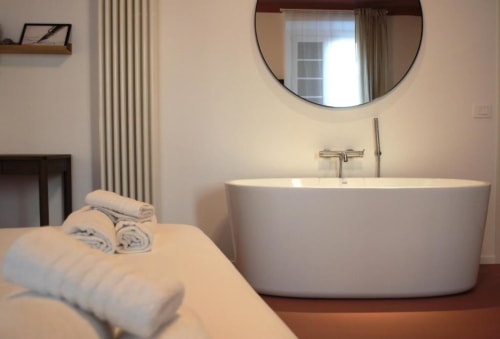 Bagno moderno con vasca freestanding e specchio rotondo al Le Dimore Del Duca Roma, camera attigua con asciugamani