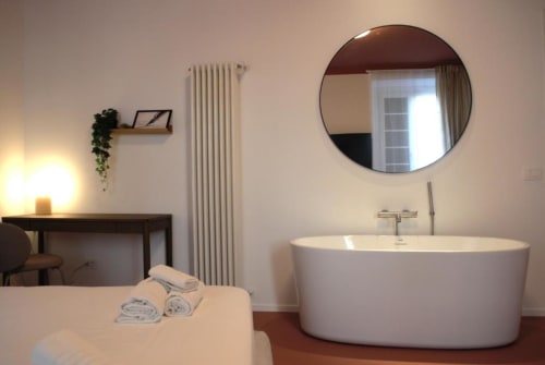 Bagno moderno a Le Dimore Del Duca Roma con vasca freestanding, specchio circolare e asciugamani sul letto