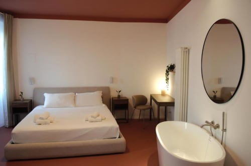 Elegante camera quadrupla con vasca indipendente, specchio ovale raffinato e letto confortevole presso Le Dimore Del Duca Roma boutique