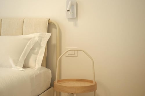 Camera da letto minimalista a Le Dimore Del Duca Roma con letto, biancheria bianca, comodino e presa elettrica.