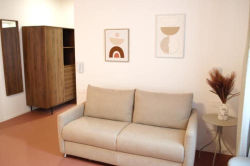 Divano letto beige in camera moderna presso Le Dimore Del Duca Roma con guardaroba in legno e arte astratta a parete