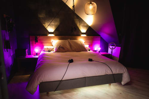 Modern attic bedroom in Vannes with mood lighting, white bedding, purple ambient lights, wooden headboard, and pendant lamp