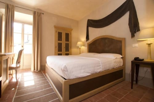 Elegante camera doppia presso l'Hotel San Giovanni Resort di Saluzzo con letto in legno, biancheria bianca e vista sul monumento dalla finestra