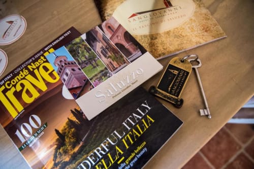 Travel guides and vintage key at Hotel San Giovanni Resort in Saluzzo, Italy, displayed on wooden desk