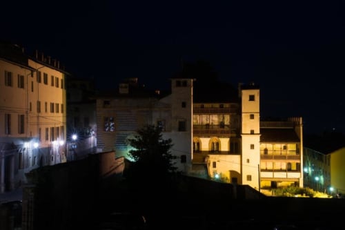 Medieval tower and historic buildings illuminated at night in Saluzzo, Italy, view from Hotel San Giovanni Resort