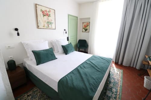 Double bedroom at Hotel Villa Roseraie in Vence with white bedding, green accents, and terracotta tile flooring