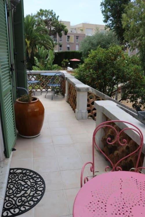 Private terrace at Hotel Villa Roseraie in Vence with pink chair, potted plant, and pool view beyond lush gardens