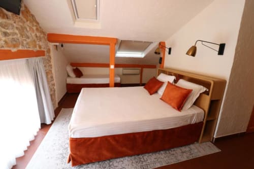 Chambre triple à l'Hôtel Villa Roseraie à Vence avec lit queen, lits superposés, accents orangés et vue sur les montagnes