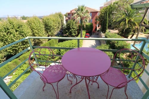 Table et chaises de bistrot violettes sur un balcon avec vue sur les jardins luxuriants de l'Hôtel Villa Roseraie à Vence