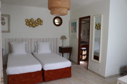 Chambre Twin Suite de l'Hôtel Villa Roseraie à Vence avec lits jumeaux, décoration murale dorée et accès à la vue sur jardin