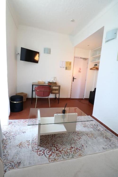Suite moderne à la Villa Roseraie à Vence avec table basse en verre, bureau, télévision et porte de salle de bain rose