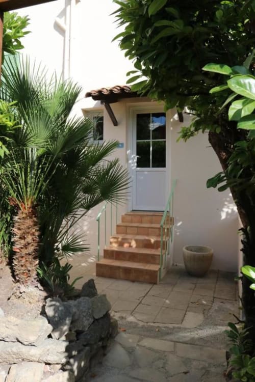 Entrée privée de la Chambre Double avec Terrasse de l'Hôtel Villa Roseraie à Vence, entourée de plantes tropicales luxuriantes et de palmiers