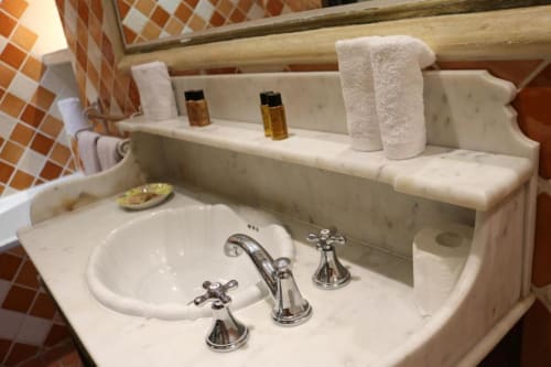 Marble bathroom sink with chrome fixtures, towels, and amenities at Hotel Villa Roseraie, Vence