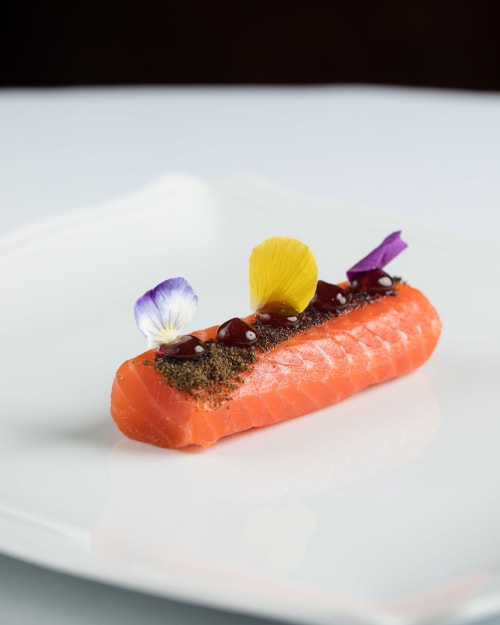Elegante salmón presentado con flores comestibles en Hotel San Giovanni Resort, Saluzzo Italia