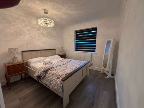 Modern bedroom at England Furnished Homes, High Wycombe, featuring queen bed, wooden nightstand, ceiling light, and blue