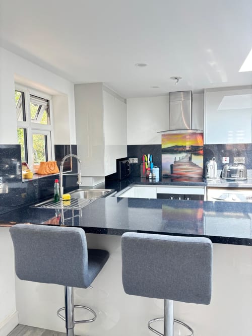 Modern kitchen with black and white cabinetry, dark speckled countertops, stainless steel appliances, and two gray bar stools