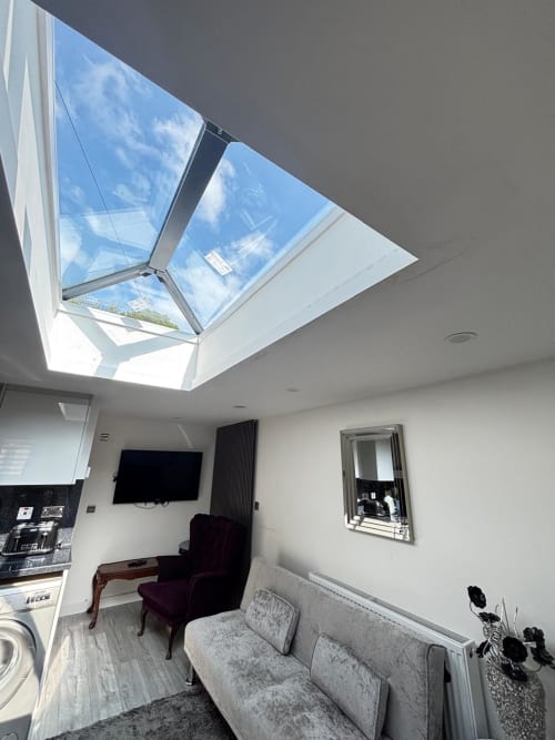 Modern living room with skylight, grey sofa, armchair, TV, and garden views at CozyNest in High Wycombe