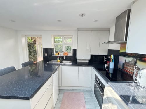 Modern kitchen with white cabinets, black countertops, stainless steel appliances, and garden view at CozyNest 2BR villa in
